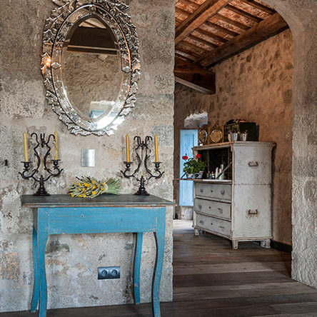 Stone walled interior with oval mirror positioned over a recycled table in a Palamós farmhouse in Catalonia, Spain
