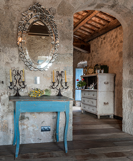 Stone walled interior with oval mirror positioned over a recycled table in a Palamós farmhouse in Catalonia, Spain