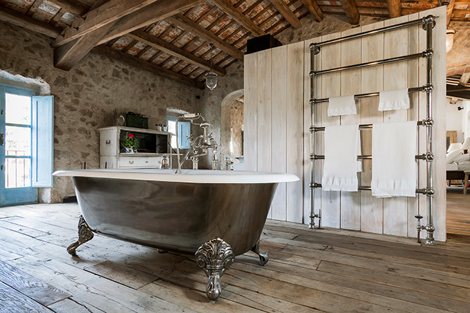 Luxury bathroom freestanding ball and claw bath tub with oversized chrome towel rail in a Palamós farmhouse in Catalonia, Spain