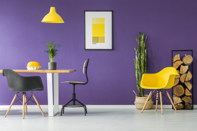 Using contrasting colour in home interior design can create a strong impact and create a space that's happy and energised like this purple room with yellow furniture and artwork.
