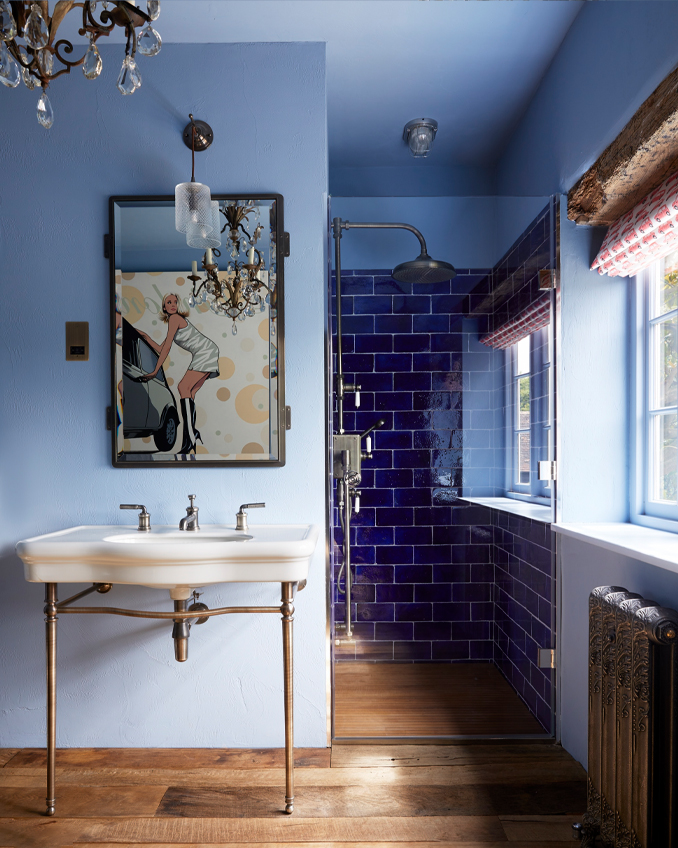 Bathroom with blue titled and blue painted walls along with a white bathroom suite. This shows that matching tiles and wall colours when combined with traditional design styles work well in the interior design of bathroom.