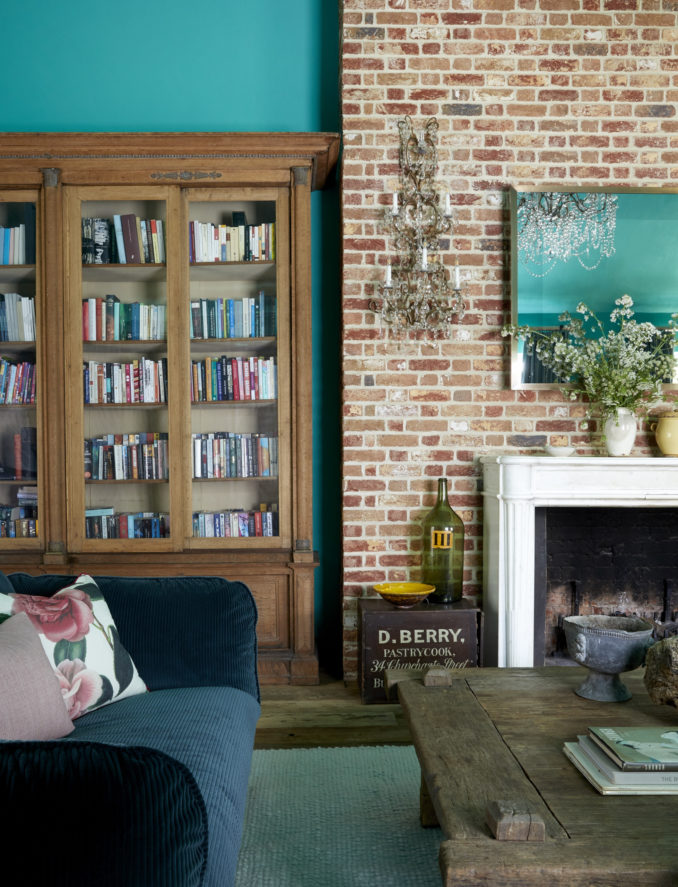 Renovated living room in a listed building in Surrey with a refurbished wooden book cabinet and bare brick wall combined with painted walls and a vintage coffee table from Azultierra.