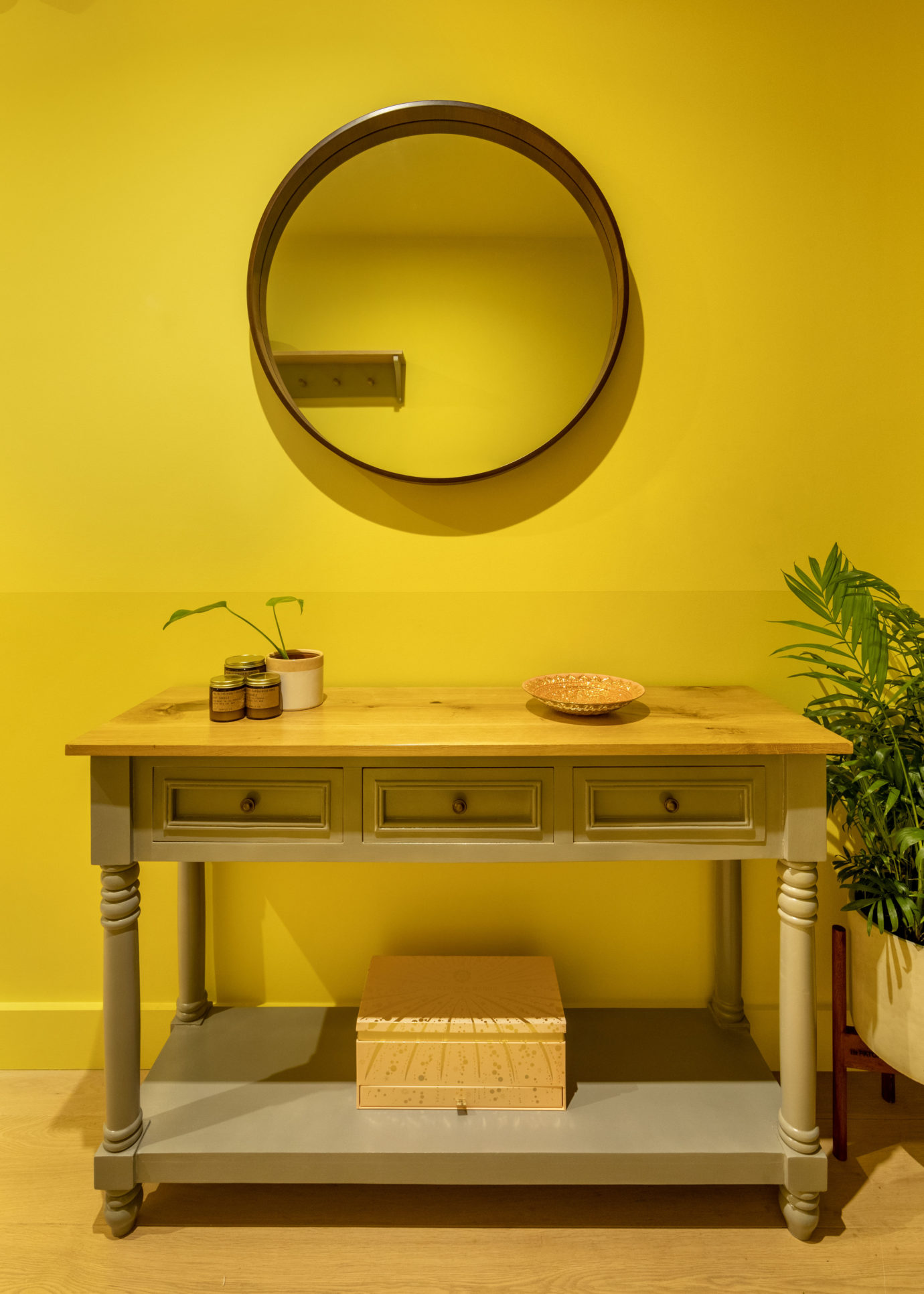East London apartment interior design table and round mirror against a bright yellow wall
